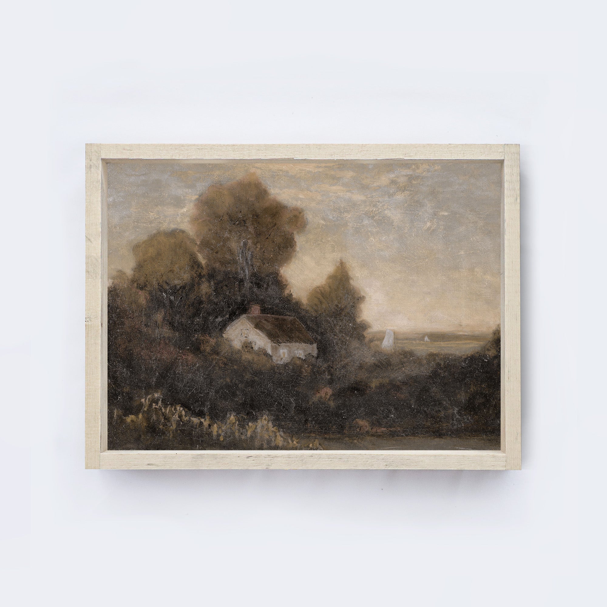 Cream coloured wood frame of a painting of a landscape with trees and a house on a white wall