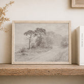 Framed landscape print of a path and trees on a wooden shelf.