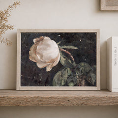 Framed artwork of a rose on a wooden shelf.