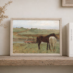 Framed painting of two horses in a landscape on a wooden shelf.