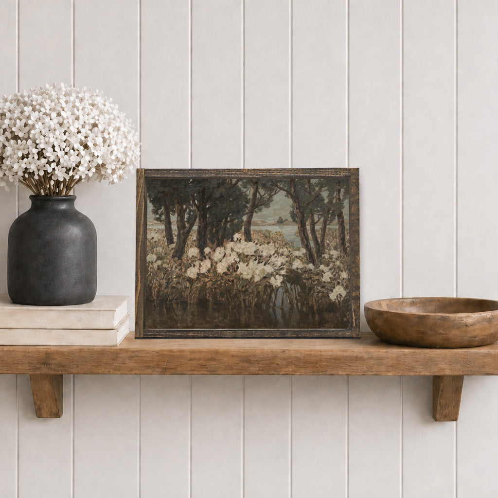 Wooden shelf with a framed artwork, vase with flowers, and wooden bowl against a light gray wall.