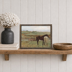 Framed artwork of two horses on a wooden shelf with decorative items.